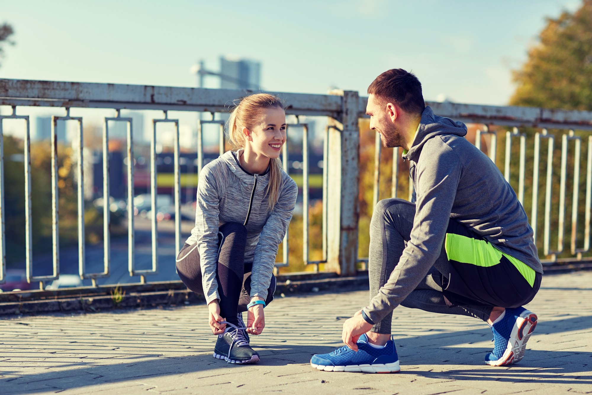 smiling couple tying shoelaces outdoors