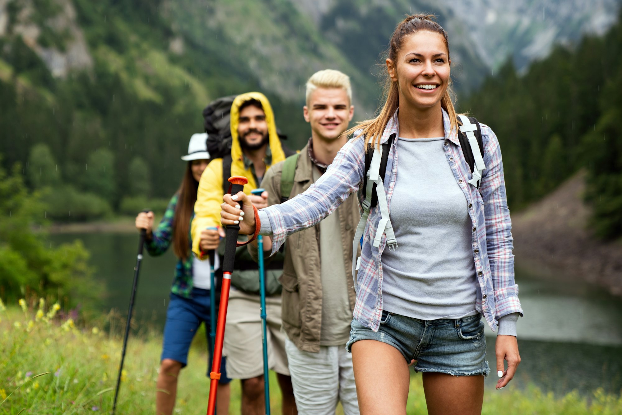 Group of smiling friends hiking with backpacks outdoors. Travel, tourism, hike and people concept