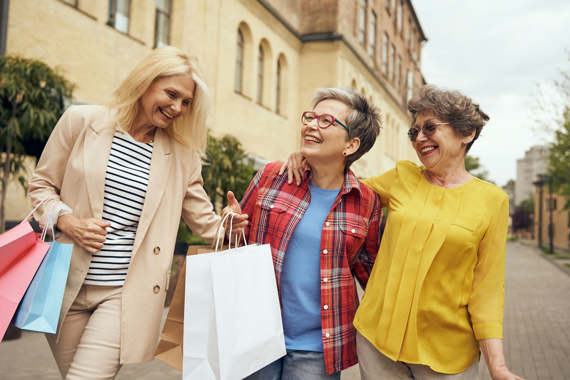 Smiling senior female friends is walking outdoors with shopping bags in the city center